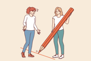 How Anxious Attachment Manifests in Adult Relationships 3 A woman uses a large red pencil to draw a line between her and someone else - setting a boundary.