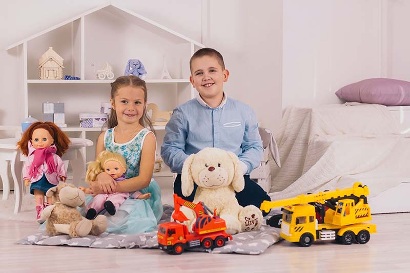Gender Socialization: Examples, Agents & Impact 1 beautiful happy caucasian children sitting in their room, boy with car, girl with doll