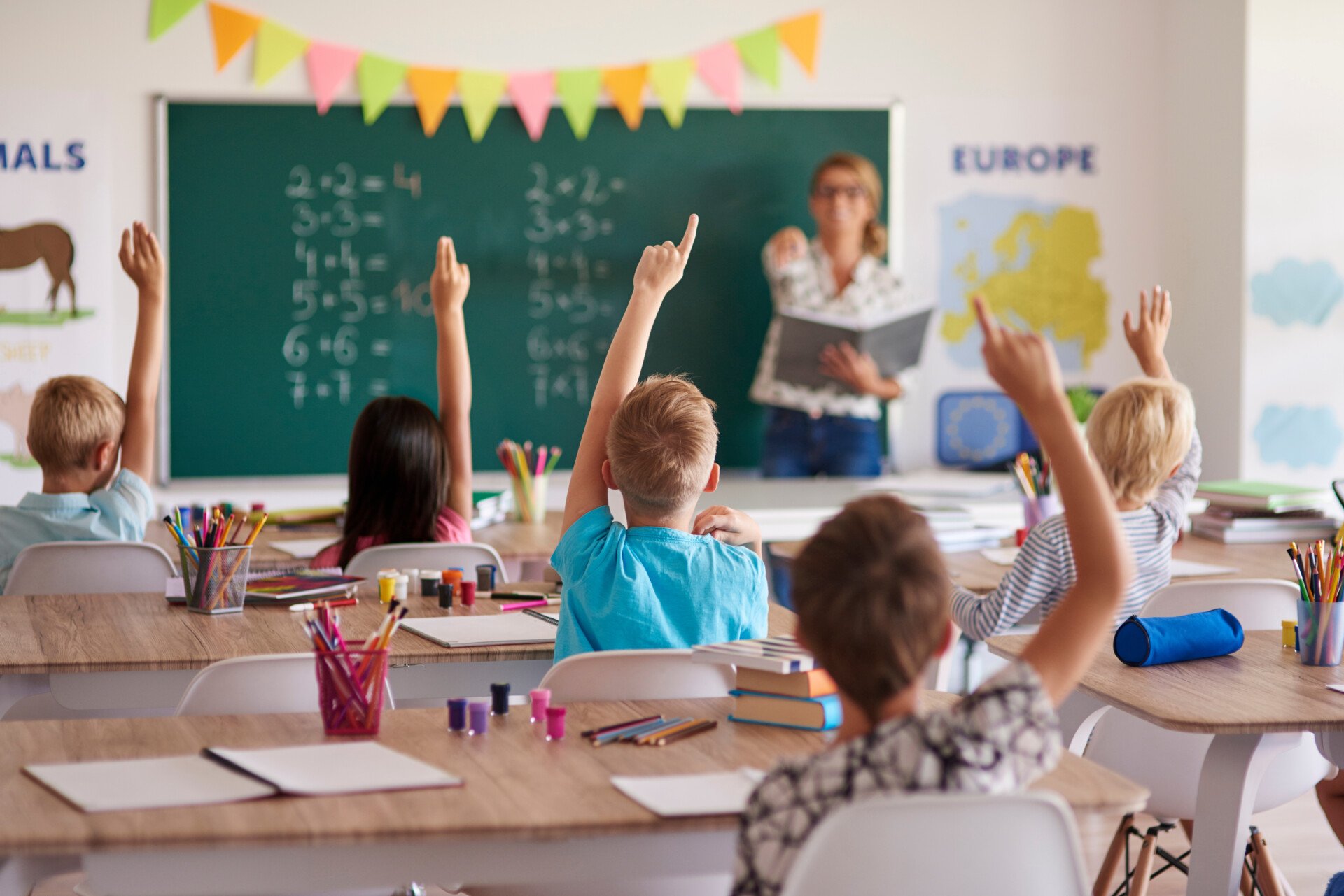 Labelling Theory (Education) 1 Classroom full of children with their hands raised. Teacher at the front chooses a child to answer the question.