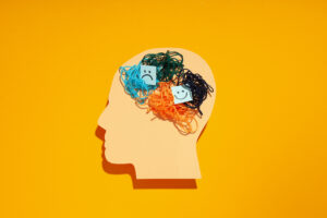 What Is a Manic Episode: Signs, & How To Manage 15 an outline of a head with messy string on the inside and a sad and happy face in the head